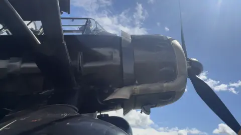 Jamie Niblock/BBC The view of a World War Two propeller aircraft from below. 