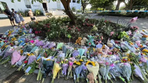 Hundreds of flowers left by a tree in a park 