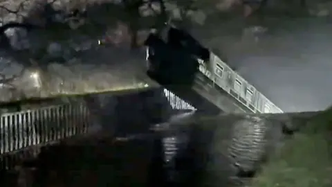 Boat teetering on edge of drop, person holding phone on bottom right side of picture