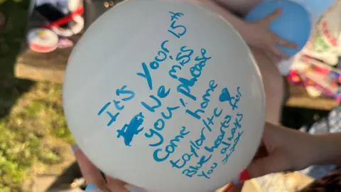 A white balloon with a birthday message written in blue pen.