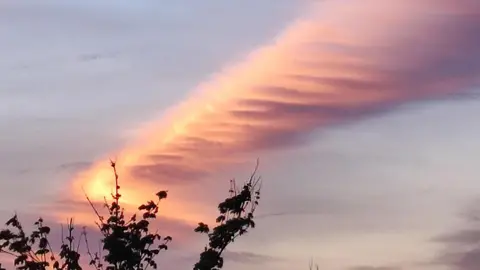 BBC Weather Watchers/Ruthie A thin cloud orange in colour and surrounded by a soft purple sky.