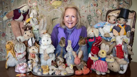Bunny Campione, wearing a purple top and scarf, sat with the rabbits of various shapes and sizes.
