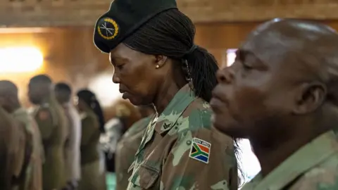 AFP A South African soldier bows her head at a funeral in Pretoria of a colleague killed during a mortar incident in DR Congo - March 2024