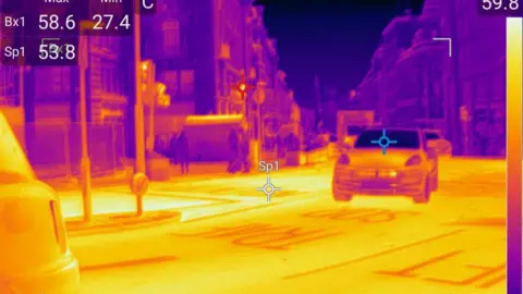 Greenpeace / TI Thermal Imaging A thermal image of a road and car. The road is yellow and the car is blue. 