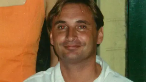 Alex McBratney Alex McBratney as a young man. He is tanned and has short, blond hair. He is wearing a white short and is smiling at the camera  