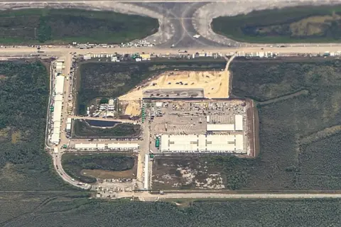 AFP via Getty Images is an air offer for the migrant detention center, called the name "Cookie crocodile," Show large areas of green and swamps with spots from the airport and the concrete airport in the middle with the buildings and vehicles that were seen on them.