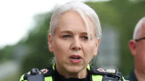 PA Media A woman with grey hair in police uniform captured mid-speech
