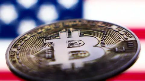 US flag displayed on a laptop screen and representation of Bitcoin cryptocurrency on 6 November, 2024.