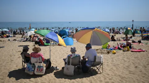 Getty Images Sunbathers relax in the sunshine on Bournemouth beach on the south coast of England on May 26, 2026, as heatwave conditions spread to parts of southeast England and London. 