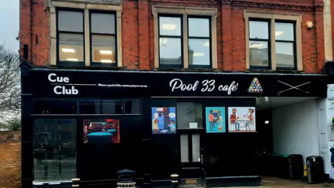 The Cue Club Exterior pic of the Cue Club- a black building with a white sign saying Pool 33 cafe 