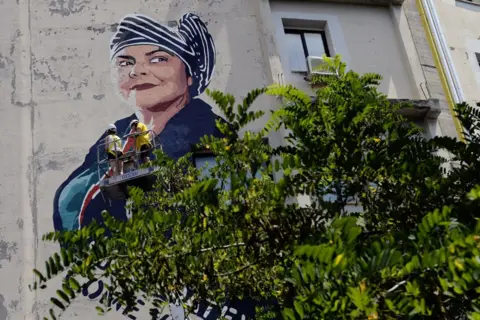 Simona Granati/Corbis via Getty Images The face of Italian writer Michela Murgia is painted by street artist Laika on a wall in Rome