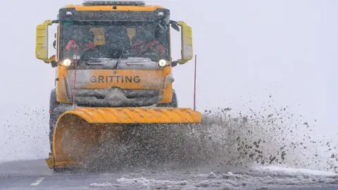 Getty Images A snow plough keeps road clear as snow falls on the North Yorkshire moors in February