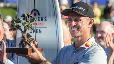 Justin Rose is presented the Championship trophy after winning the Farmers Insurance Open
