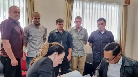 'Bali Nine' (L-R, background) Martin Eric Stephens, Michael William Czugaj, Scott Anthony Rush, Mathew James Norman and Si Yi Chen inside a room in Bali International Airport during a handover process for their return