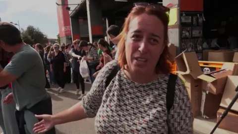 Veronica Briz, a volunteer helping flood victims in Valencia, stands in front of an aid distribution queue