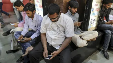Getty Images Passengers can be seen staring at their smartphones at Mumbai Central railway station.