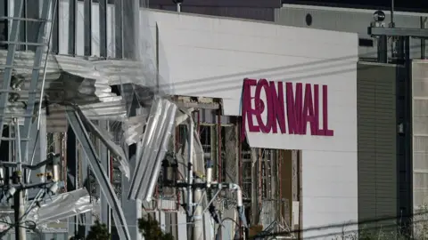 A damaged building with the words Aeon Mall on its side