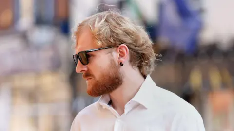 PA Media A image of a man with blond hair and an earring wearing sunglasses.