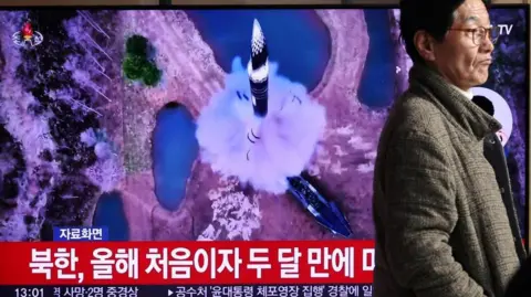 A man walks past a TV broadcasting a news report on North Korea firing a ballistic missile out to sea off its east coast, in Seoul, South Korea