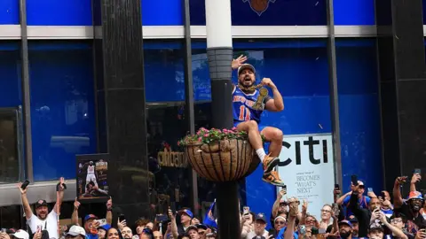 AFP via Getty Images a Knicks fan sitting inside a flower basket attached to a lamppost