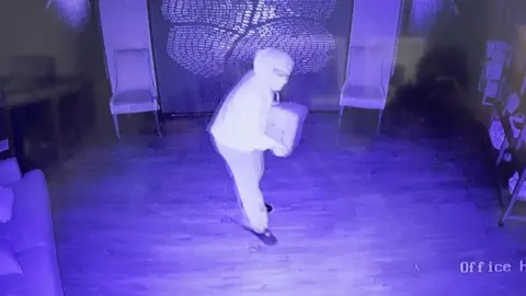 CCTV of a masked person holding a canister