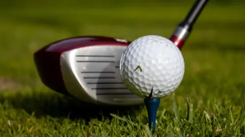 Picture showing golf driver next to a golf ball on a tee