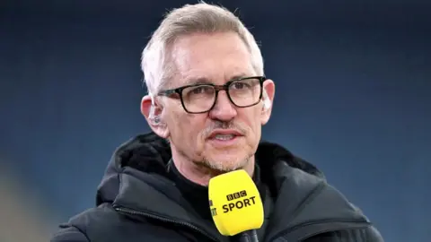 PA Media Gary Lineker pictured on a football pitch in 2021 holding a BBC Sport microphone
