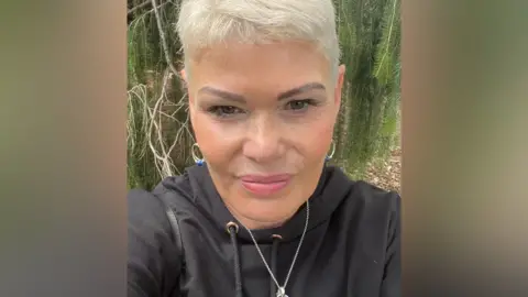 Heather Lamont A selfie of Heather in a black hoodie with short, blonde hair.