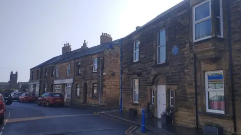 Matthew Connolly  A terraced Victoria street running down to the clock tower at Amble