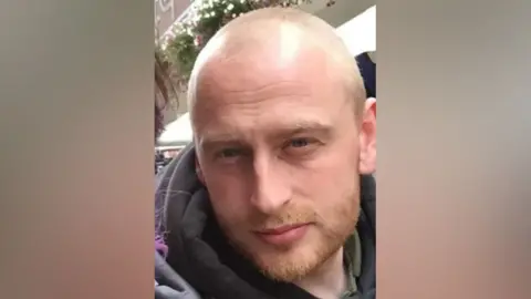 Family photograph An image of Lee Star, whose face is close to the camera for a selfie. He has a light, close-cropped beard and a shaved head