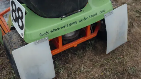 Harry George Hall Lawn mower back with the phrase - 'Roads! Where we're going we don't need roads"'