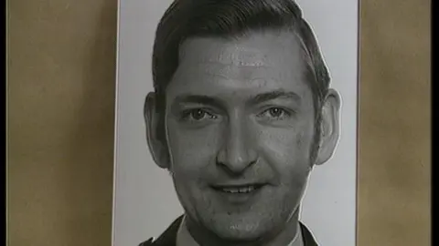 PA Media A photograph of Desmond Conroy. It is a black and white photo of Mr Conroy, who is smiling at the camera. He is wearing a police uniform that is just out of shot.