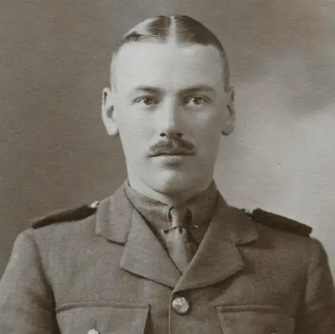Morganfourman.com Noel Downing pictured in 1916 as a newly commissioned Second Lieutenant in the Welsh Guards. He has short hair and a moustache and is wearing army uniform. 