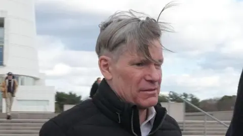 AFP A headshot of Matthew Smith standing outside court. His grey hair is flying in the wind.