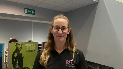 Emma Kessie in a staff uniform smiling at the camera.