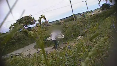 Cornwall Council Hidden camera footage of two men dumping a mattress at a fly-tipping hot spot in Cornwall. It is a lay-by in the countryside.