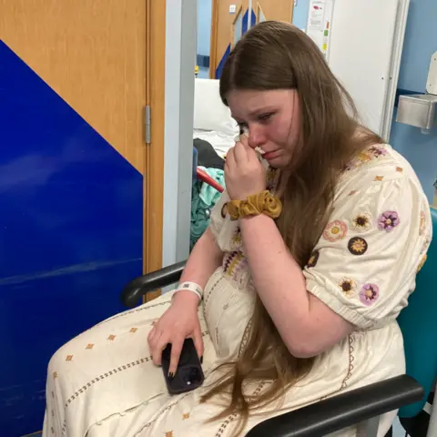 Johanna Johanna sitting in a hospital padded chair crying