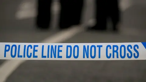 White police tape with blue writing reads: 'POLICE LINE DO NOT CROSS'