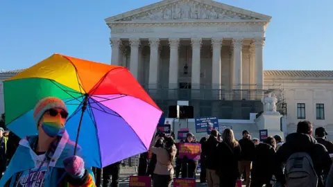 A protester with a rainbow coloured umbrella stands outside the US Supreme Court