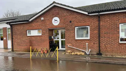 Adrian Harms/BBC Exterior of a building with flooding out on the road