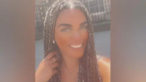 Family photograph Robyn Eve Maines smiling with her hand in her long braided hair