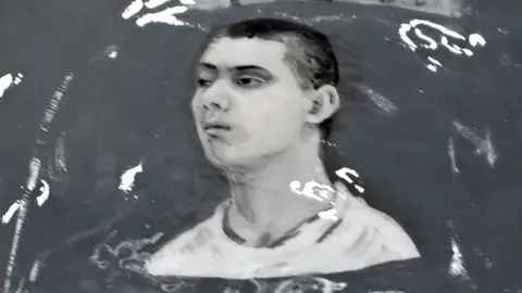 Reuters Close up of the helmet featuring a black and white illustration of Fedir Yepifanov. He is drawn from the side and has short, dark hair.