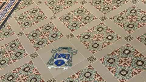 Purbek flooring with ornate detailed patterns in green and red with a cathedral crest emblem.