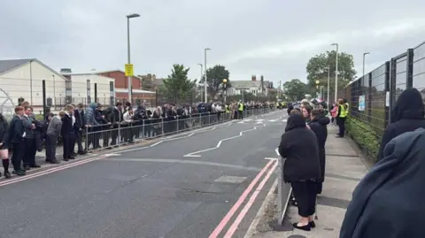 LDRS Hundreds of school pupils wearing uniform line the streets surrounding Armfield Academy in Blackpool. They are paying their respects ahead of the funeral cortege for teacher Pat Burns.