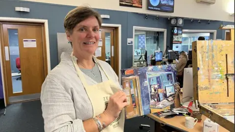 BBC Rosanne Guille holding painting in front of radio studio