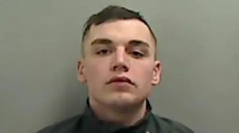 Mugshot of McElvaney. He is clean shaven with short dark hair.