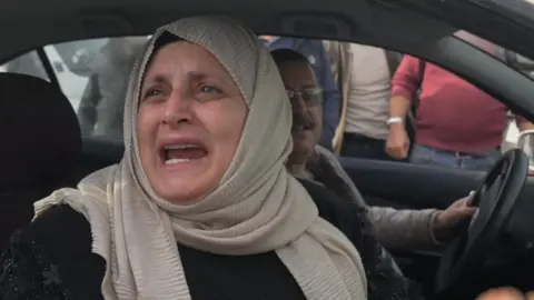 A woman in the passenger seat of a car welcomes the news that Assad has been overthrown