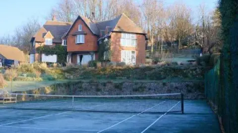 The tennis courts at 15 Chantry Avenue, with a red brick house in the background.