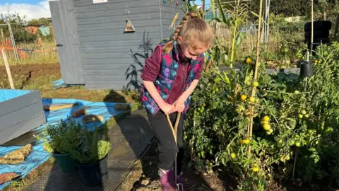 Kate Bradbrook/BBC Penny digging in a purple fleece in her allotment