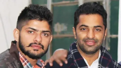 Lawrence Bishnoi and Vicky Middukhera both look at the camera - Bishnoi has a carefully groomed moustache and Middukhera is smiling and wearing a checked scarf.